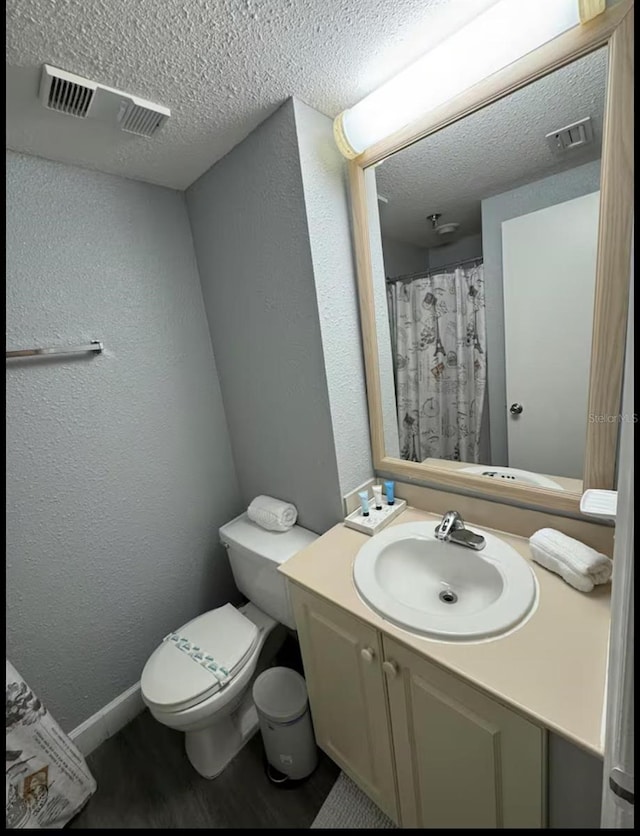 bathroom with a textured wall, a textured ceiling, visible vents, and toilet
