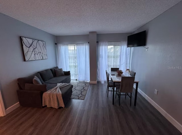 living area with a textured ceiling, baseboards, and dark wood finished floors