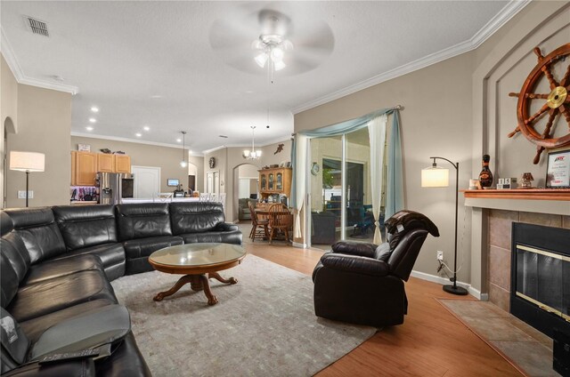 625 Waterland Ct, Orlando, FL 32828 - living area with a ceiling fan, a fireplace, light wood-style flooring, visible vents, and arched walkways