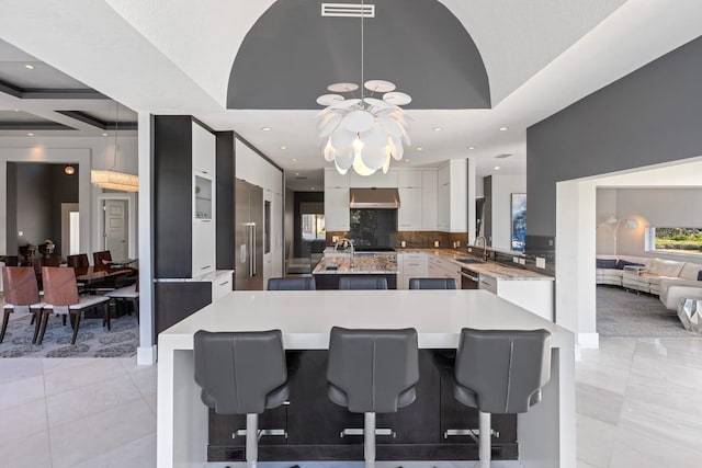 9000 Shawn Park Pl, Orlando, FL 32819 - kitchen with an island with sink, a notable chandelier, light countertops, a sink, and white cabinets