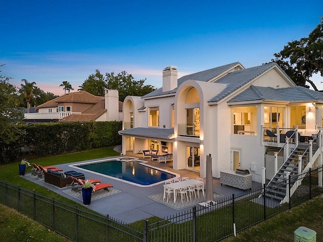 9000 Shawn Park Pl, Orlando, FL 32819 - back of house at dusk featuring a fenced backyard, a balcony, stucco siding, and a patio