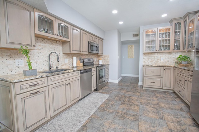 701 Denton Rd, Winter Park, FL 32792 - kitchen with baseboards, a sink, light stone countertops, appliances with stainless steel finishes, and glass insert cabinets