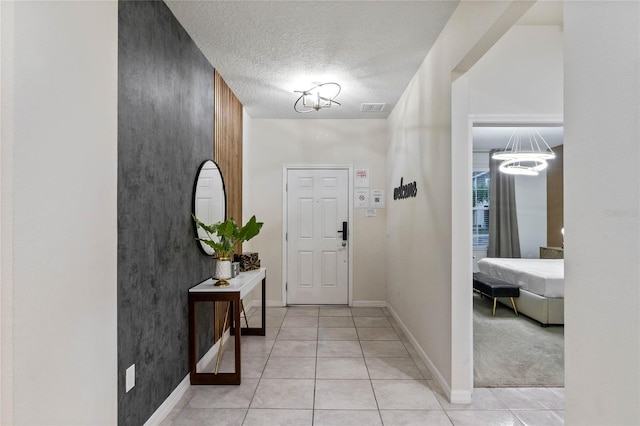 4305 Lana Ave, Davenport, FL 33897 - foyer entrance with light tile patterned flooring, a textured ceiling, visible vents, baseboards, and an inviting chandelier