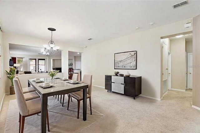 dining space featuring light colored carpet, visible vents, a chandelier, and baseboards