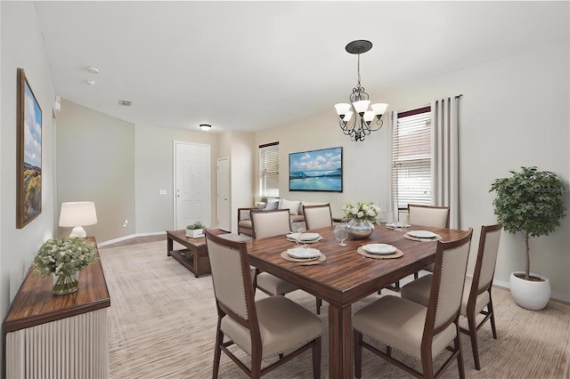 dining room with an inviting chandelier, visible vents, light carpet, and baseboards