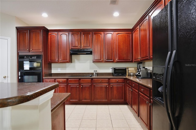 kitchen with black appliances, reddish brown cabinets, and dark countertops