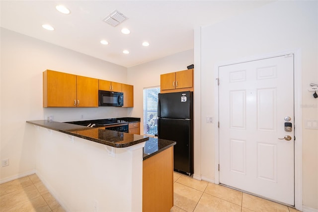 kitchen with light tile patterned floors, black appliances, visible vents, a peninsula, and brown cabinetry