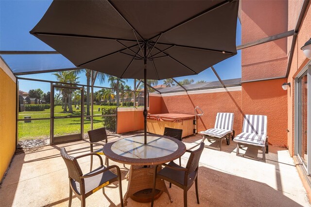 view of patio / terrace with glass enclosure, outdoor dining space, and a hot tub