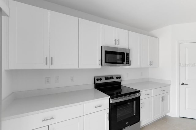 kitchen featuring light tile patterned floors, light countertops, white cabinetry, and appliances with stainless steel finishes