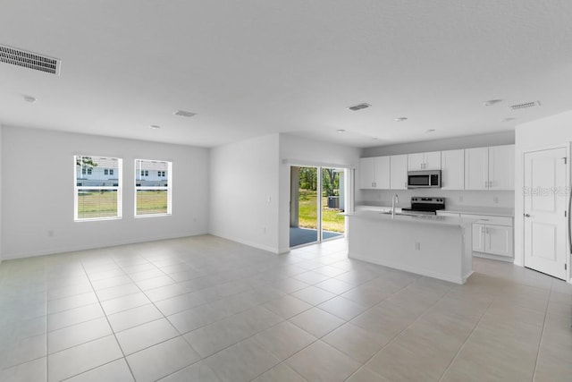 kitchen featuring stainless steel appliances, a kitchen island with sink, open floor plan, visible vents, and light countertops