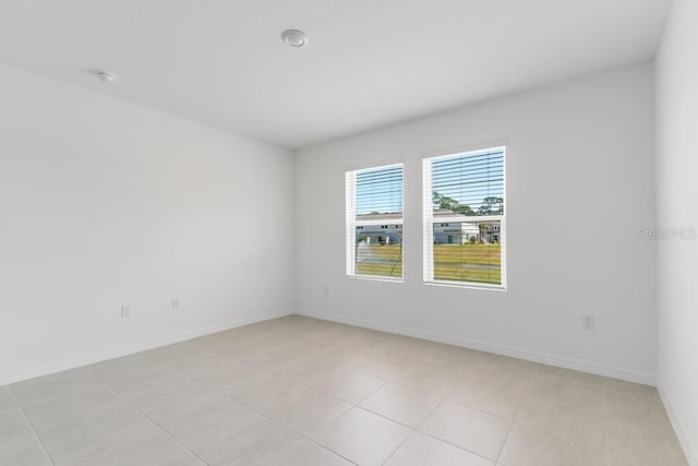 spare room featuring baseboards and light tile patterned floors