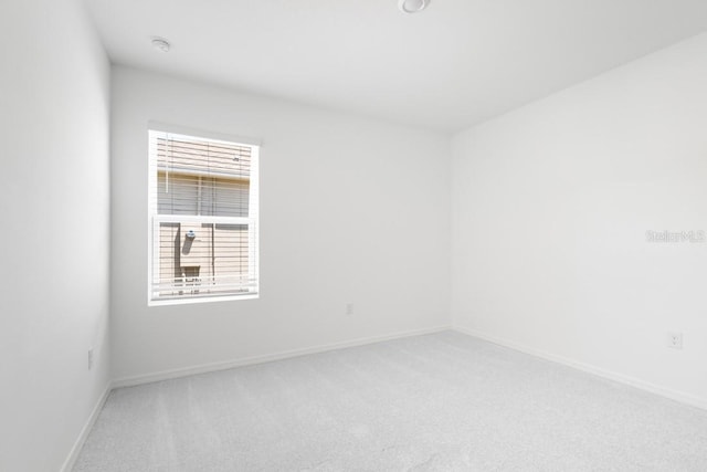spare room with baseboards and light carpet