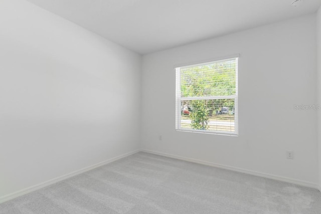 empty room featuring light colored carpet and baseboards