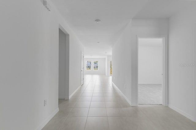 hall featuring baseboards and light tile patterned flooring