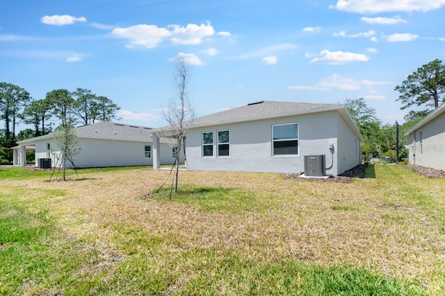 rear view of property with stucco siding, a yard, and cooling unit