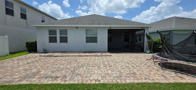 3043 Beaver Creek Dr, Kissimmee, FL 34746 - back of house featuring a trampoline, a patio area, a sunroom, stucco siding, and a shingled roof