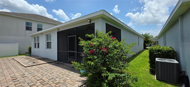 3043 Beaver Creek Dr, Kissimmee, FL 34746 - view of property exterior featuring central air condition unit, stucco siding, a patio, and a sunroom