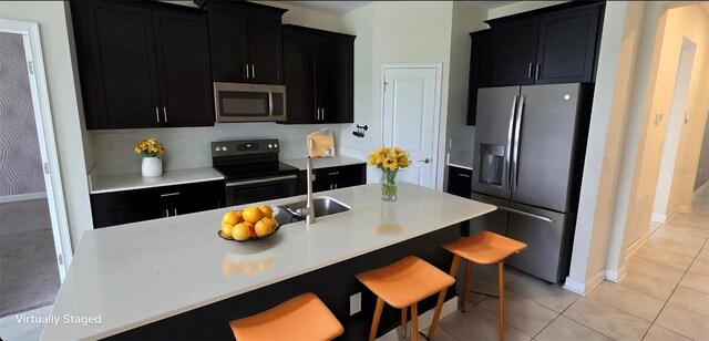 3043 Beaver Creek Dr, Kissimmee, FL 34746 - kitchen with appliances with stainless steel finishes, dark cabinetry, a sink, a breakfast bar area, and light countertops