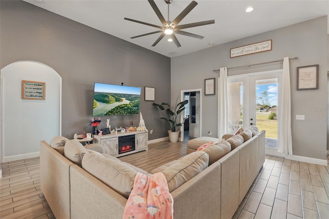 living area featuring baseboards, ceiling fan, and wood tiled floor