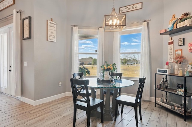dining space with baseboards, wood finish floors, and an inviting chandelier