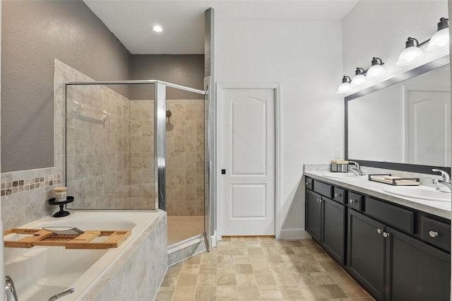 full bathroom featuring a shower stall, double vanity, a sink, and a garden tub