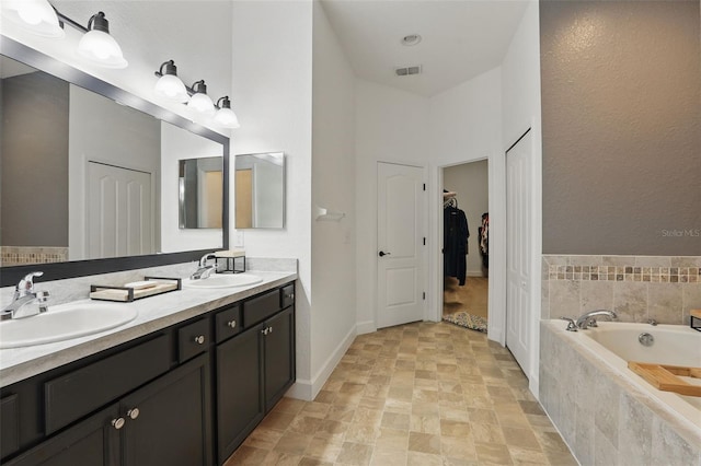 bathroom with a walk in closet, a sink, a garden tub, visible vents, and double vanity