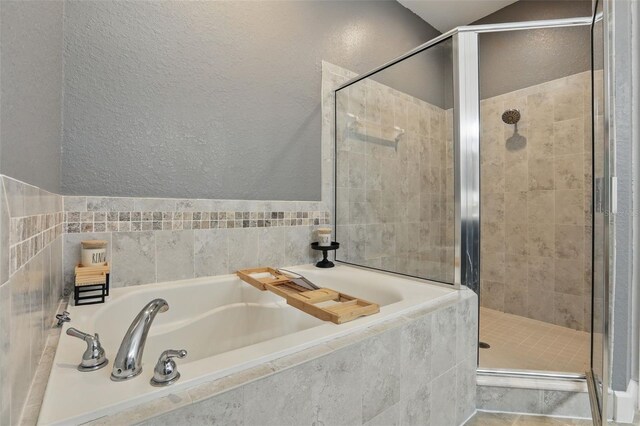bathroom with a garden tub, a textured wall, and a stall shower