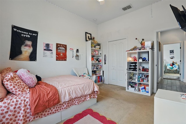 carpeted bedroom with a closet, visible vents, and a ceiling fan