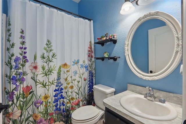bathroom featuring a shower with curtain, toilet, vanity, and a textured wall