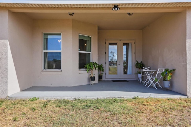 view of exterior entry featuring stucco siding and french doors