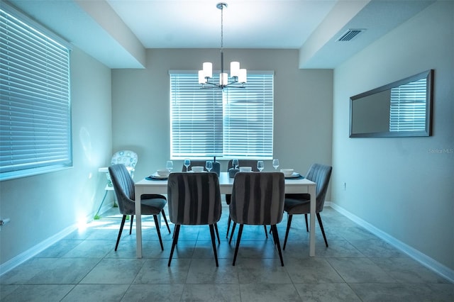 tiled dining area featuring baseboards, a wealth of natural light, visible vents, and a chandelier