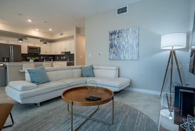 living room featuring baseboards, visible vents, and recessed lighting