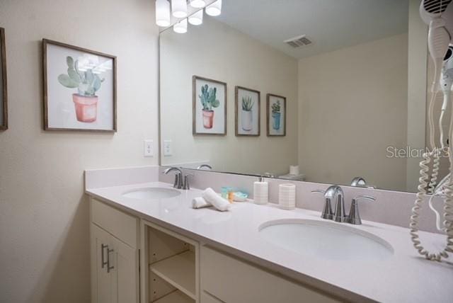 bathroom featuring double vanity, visible vents, and a sink