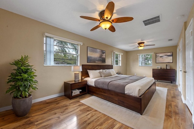 bedroom featuring baseboards, light wood-style floors, ceiling fan, and visible vents