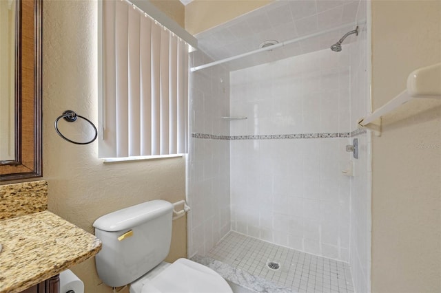 bathroom featuring a tile shower, toilet, and a textured wall