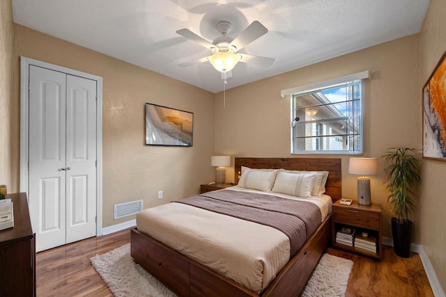 bedroom featuring baseboards, visible vents, a ceiling fan, a closet, and wood finished floors