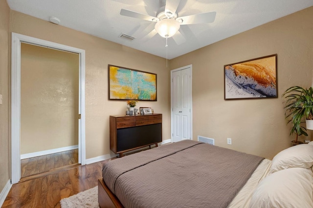 bedroom featuring wood finished floors, baseboards, a closet, and visible vents