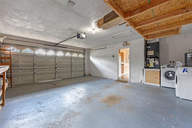 garage featuring heating unit, washing machine and dryer, and a garage door opener