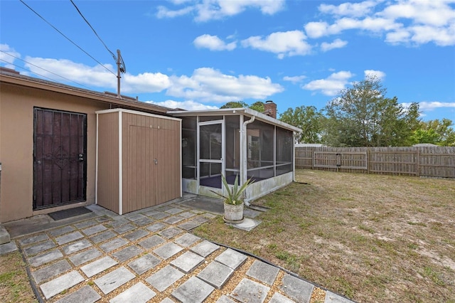 rear view of property featuring a sunroom, stucco siding, fence, a yard, and a chimney