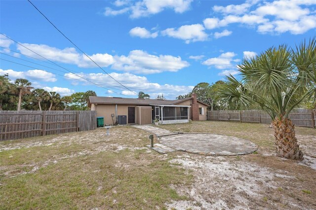 back of property featuring a fenced backyard, a sunroom, stucco siding, and a lawn