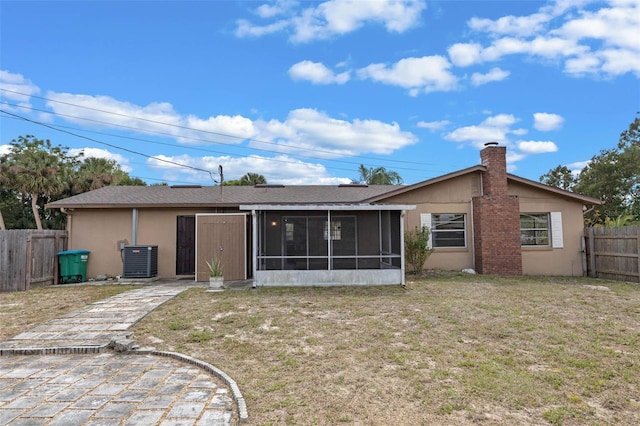 rear view of property with cooling unit, a sunroom, stucco siding, fence private yard, and a lawn