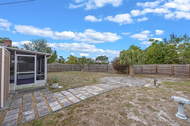 view of yard featuring a fenced backyard, a sunroom, and a patio area