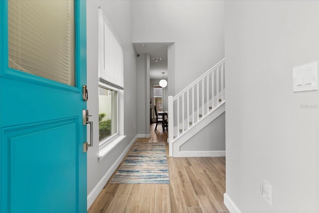 foyer entrance featuring wood finished floors, baseboards, and stairs