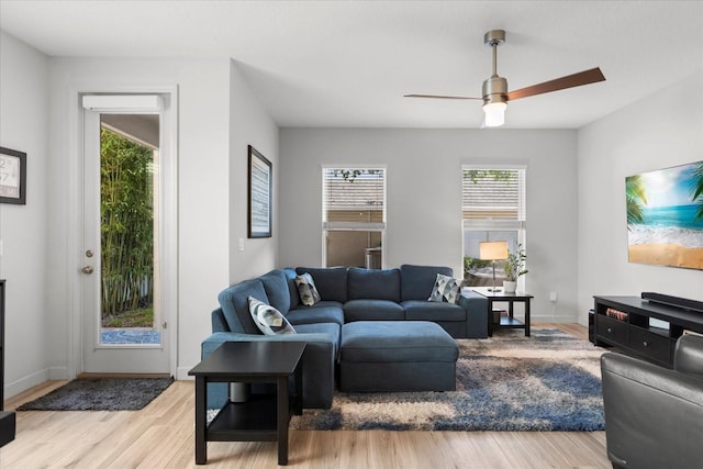 living area featuring ceiling fan, baseboards, and light wood-type flooring