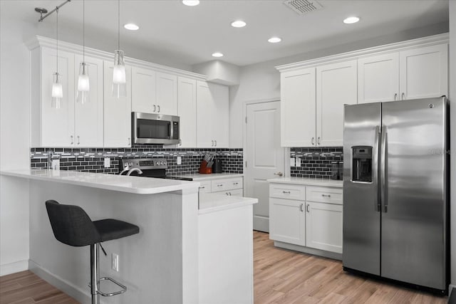 kitchen with a kitchen breakfast bar, stainless steel appliances, white cabinets, a peninsula, and visible vents
