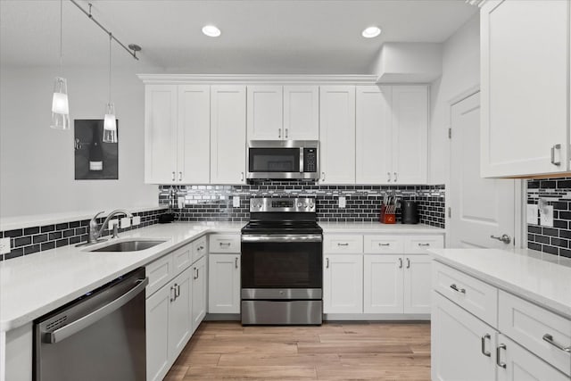 kitchen with white cabinets, light countertops, stainless steel appliances, and a sink