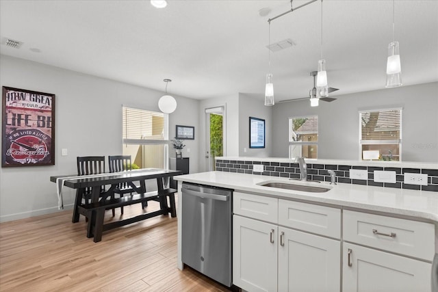 kitchen featuring a sink, dishwasher, decorative light fixtures, white cabinetry, and visible vents