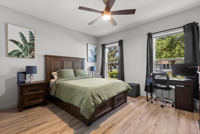 bedroom with light wood finished floors, a ceiling fan, and baseboards