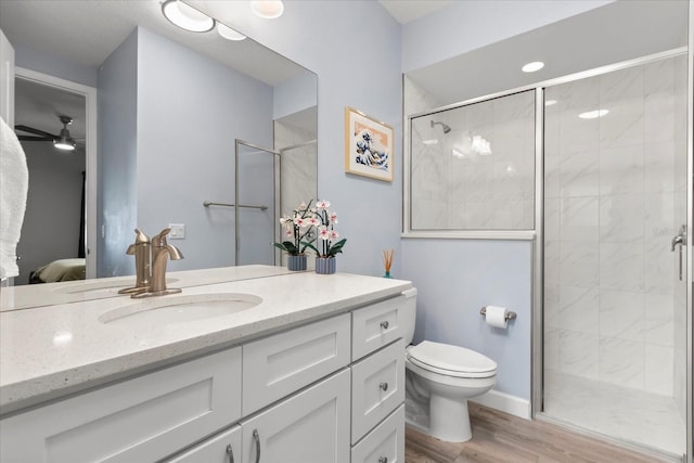 full bath with wood finished floors, toilet, vanity, a stall shower, and ceiling fan