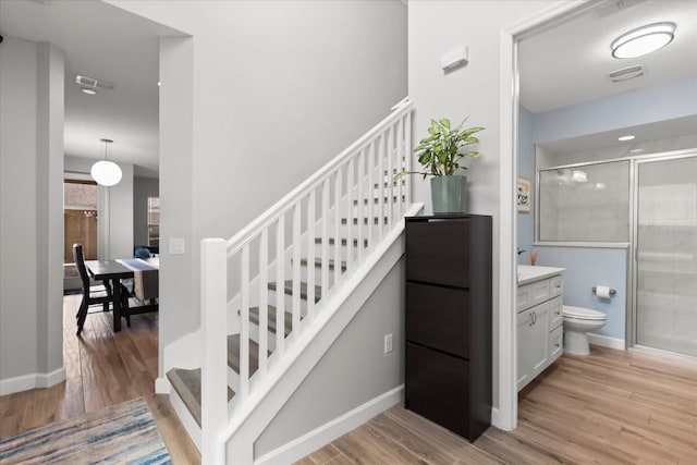 stairway with wood finished floors, visible vents, and baseboards